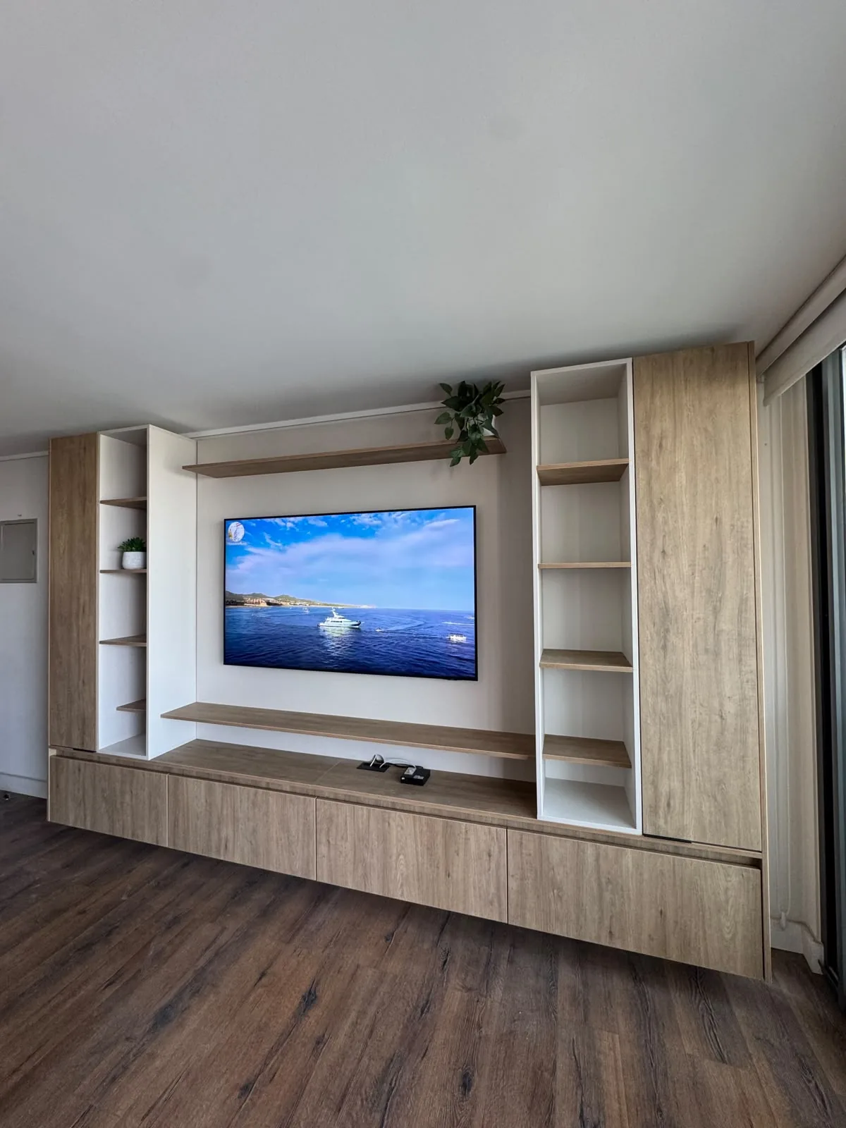Rack de living a medida en melamina tono madera clara, con mueble flotante, estanterías abiertas y televisor, en Las Condes